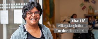 Altagsbegleiterin mit kurzen schwarzen Haaren laechelt freundlich in die Kamera